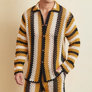 Puede incluir: Una camisa de crochet a rayas negras, blancas y amarillas con cierre de botones.