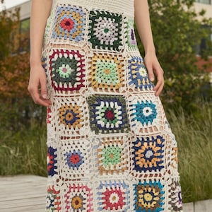 May include: A white crochet skirt with a colorful patchwork design. The skirt is made of squares of different colors and patterns, including red, blue, green, yellow, and pink.