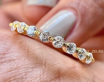 May include: A gold band ring with a row of small, clear round gemstones.