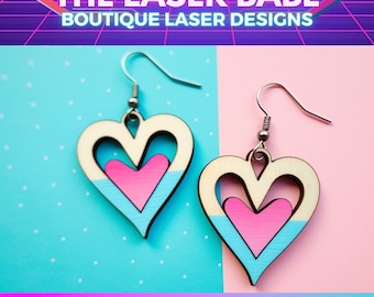 Puede incluir: Un par de pendientes en forma de corazón con un diseño recortado. Los pendientes están pintados en un esquema de color azul claro y rosa. Los pendientes cuelgan de ganchos plateados. El texto "CUTIE HEARTS DANGLES" se muestra debajo de los pendientes.