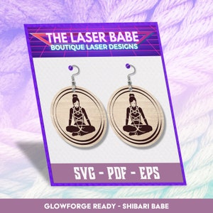 May include: A pair of wooden earrings featuring a laser-cut design of a woman in a shibari pose. The earrings are round and have a light wood colour. The design is in black and the text "SVG - PDF - EPS" and "GLOWFORGE READY - SHIBARI BABE" is below the earrings.