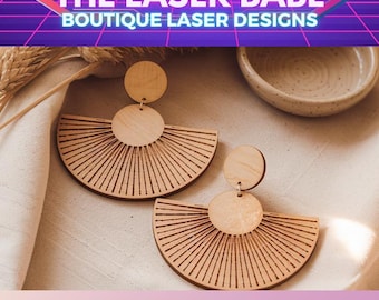 May include: Wooden laser-cut earrings in a fan design. The earrings are light brown with a circular top and a larger, semi-circular bottom with linear cutouts. The text "THE LASER BABE" and "BOUTIQUE LASER DESIGNS" are at the top, and "FAN DANGLES" at the bottom.