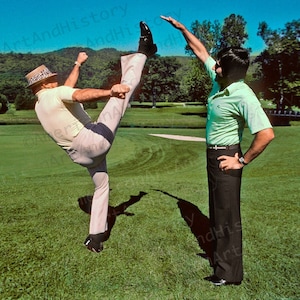 Pode incluir: Dois homens em um campo de golfe, um está chutando a perna para o alto enquanto o outro homem observa com os braços levantados.