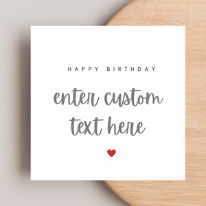 Op de afbeelding: Een vierkante witte kaart met de zwarte tekst HAPPY BIRTHDAY bovenaan, gevolgd door de grijze cursieve tekst enter custom text here, en een klein rood hartje onderaan in het midden van het kaartontwerp.