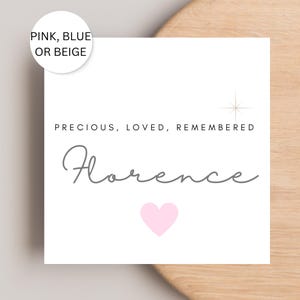 May include: A white square card with the name "Florence" in gray script, a pink heart, and the words "PRECIOUS, LOVED, REMEMBERED." A circular label at the top says "PINK, BLUE OR BEIGE."