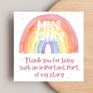 May include: A watercolour rainbow with the name "MISS JONES" written in white on the arch. The rainbow is on a white background with scattered silver glitter stars. The text below the rainbow reads "Thank you for being such an important part of my story."