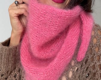 May include: A vibrant pink, fluffy scarf is draped around the neck. The scarf is made of a soft, fuzzy material. The person wearing the scarf is also wearing a brown sweater with a unique open knit design.