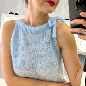 Puede incluir: Un top de punto azul claro con una sección inferior blanca y tirantes anudados. La parte superior está hecha de un material suave y difuso. El estilo es casual y femenino. Adecuado para usar en capas o solo.