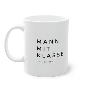 Könnte beinhalten: Weiße Keramiktasse mit schwarzem Text, der "MANN MIT KLASSE - ICH. LEHRER." lautet.