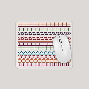 May include: A white computer mouse sits on a patterned mousepad. The mousepad has a cream background with colourful horizontal bands of geometric designs in red, green, purple, and blue. The mouse is white.