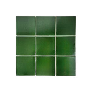 May include: Nine square, glossy, emerald green tiles arranged in a three-by-three grid. The tiles have a smooth, reflective surface and are evenly spaced, with thin, light-colored grout lines separating them. The overall effect is clean and modern.