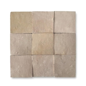 May include: A grid of nine square tiles arranged in a three-by-three pattern. Each tile features a smooth, matte surface in a muted, earthy beige tone with subtle variations in color and texture across the individual pieces of the set.
