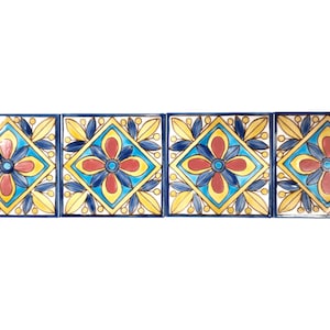 May include: A row of four square ceramic tiles with a blue, yellow, and red floral pattern. The tiles are arranged in a horizontal line.