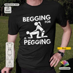 Könnte beinhalten: Schwarzes Unisex-T-Shirt mit dem weißen Text "BEGGING FOR A PEGGING". Das Shirt zeigt eine Grafik von zwei Figuren in einer sexuellen Position. Das Shirt besteht aus Bella+Canvas 3001 Material und ist anpassbar.
