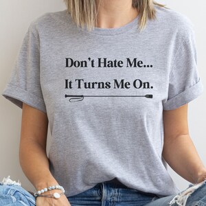 Könnte beinhalten: Graues T-Shirt mit dem Text "Don't Hate Me... It Turns Me On." und einer schwarzen Peitschengrafik.