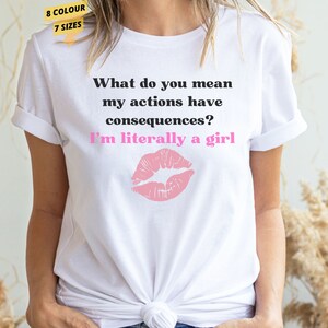 May include: White t-shirt with a pink lip print and the text "What do you mean my actions have consequences? I'm literally a girl."