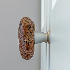 以下が含まれることがあります： 銀色の土台が付いた、茶色と赤の石製のドアノブのクローズアップ。