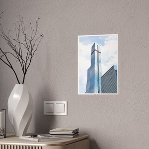 May include: A framed photograph of a tall, modern skyscraper with a blue glass facade. The building is set against a cloudy sky.