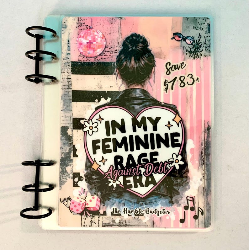 May include: A planner with a pink and black design. The cover features an illustration of a woman in a leather jacket with the text "IN MY FEMININE RAGE AGAINST DEBT ERA". Additional text includes "Save $783+" and "The Humble Budgeter".