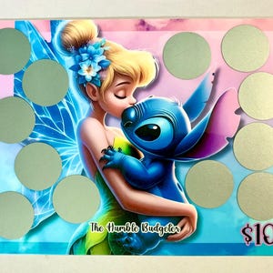 May include: A colorful rectangular scratch-off card featuring a cartoon fairy kissing a blue alien. The card has a blue, pink, and purple background with ten silver scratch-off circles. The text "The Humble Budgeter" and "$100" are visible.