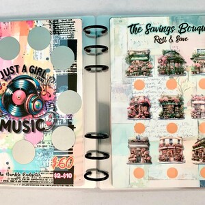 May include: A clear binder with pages featuring colorful designs and text. One page says "JUST A GIRL WHO LOVES MUSIC" with a record and headphones graphic. The other page says "The Savings Bouquet Roll & Save" with illustrations of buildings.