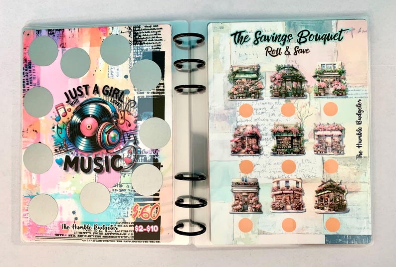 May include: A clear binder with pages featuring colorful designs and text. One page says "JUST A GIRL WHO LOVES MUSIC" with a record and headphones graphic. The other page says "The Savings Bouquet Roll & Save" with illustrations of buildings.