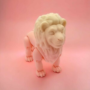 May include: A white plastic lion figurine with a detailed mane and articulated limbs. The lion is standing on a pink background.