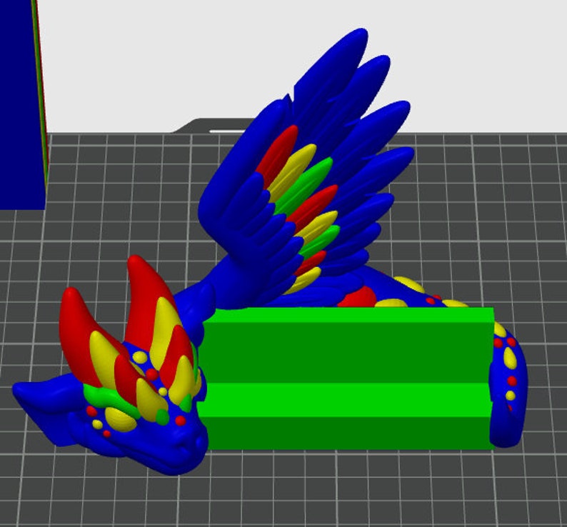 May include: A blue, red, yellow, and green 3D printed dragon phone stand. The dragon has wings and a colorful, spotted body. The stand has two slots for phones.