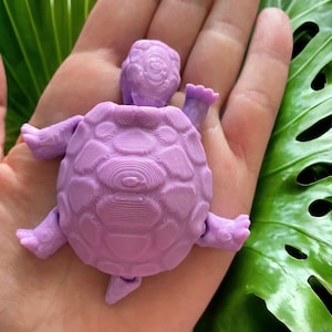 May include: A small, purple, 3D printed turtle figurine with a detailed shell and legs.
