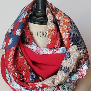 Puede incluir: Una bufanda infinita floral roja, blanca y azul con forro rojo. La bufanda está hecha de una tela suave y ligera, perfecta para agregar un toque de color a cualquier atuendo.