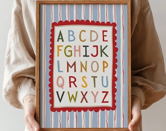 May include: A framed alphabet print with a blue and white striped background. The alphabet is displayed in colorful letters within a red scalloped border. The frame is a light brown color. The words "Download Snack" are in the bottom left corner.