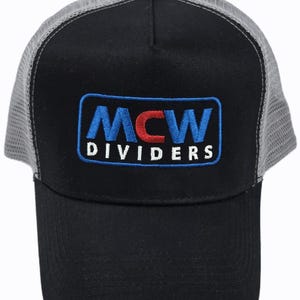 May include: Black baseball cap with a grey mesh back. The front has an embroidered patch with the letters "MCW" in blue and red, and the word "DIVIDERS" in white.