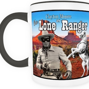 May include: White ceramic mug with a black rim featuring a vintage image of Clayton Moore as the Lone Ranger. The image shows him in his signature mask and hat, holding a gun, with his horse in the background. The text "Clayton Moore as the Lone Ranger" is printed in black on the mug.