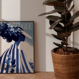 May include: A framed print of a blue and white illustration of a woman wearing a hat with the word "VOGUE" printed on the top of the frame.