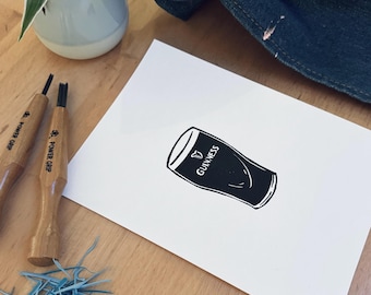 May include: A white sheet of paper with a black and white illustration of a pint glass of Guinness beer. The glass is filled with black liquid and has the word "GUINNESS" printed on the side.