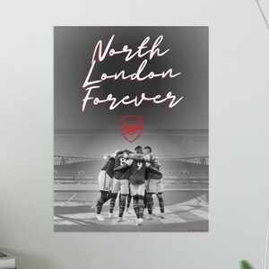 May include: Black and white photo of a group of soccer players celebrating a victory. The players are wearing their team uniforms and are huddled together in a circle. The text "North London Forever" is written in red on a gray background. The Arsenal crest is also visible in red.