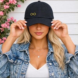May include: A black baseball cap featuring an embroidered yellow infinity symbol on the front centre. The cap has a curved brim and a structured crown, constructed from a solid fabric material with a classic six-panel design and a button on top.