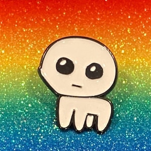 May include: White enamel pin with a cartoon character with large eyes and a simple mouth. The character is standing on a rainbow glitter background.