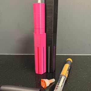 Op de afbeelding: Twee zwarte en roze penvormige insuline-injectoren met een heldere naald en een gele en heldere insulinepen.
