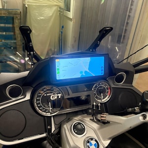 Op de afbeelding: Motorfietsdashboard met een digitaal display met een kaart. Het dashboard bevat meters, luidsprekers en de tekst "K 1600 GT". De motorfiets heeft een zwart-zilveren kleurenschema.