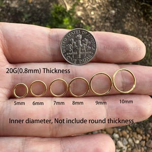 May include: Six gold hoop earrings of different sizes, ranging from 5mm to 10mm in diameter. The earrings are 0.8mm thick and are shown on a hand holding a US dime for size comparison.