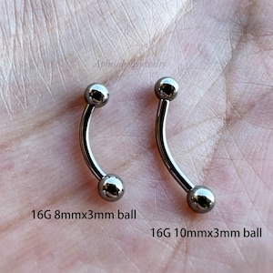 May include: Two silver curved barbell piercings with 3mm balls. The barbell on the left is 8mm long and the barbell on the right is 10mm long. 16G 8mmx3mm ball and 16G 10mmx3mm ball.