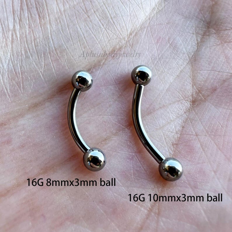 May include: Two silver curved barbell piercings with 3mm balls. The barbell on the left is 8mm long and the barbell on the right is 10mm long. 16G 8mmx3mm ball and 16G 10mmx3mm ball.