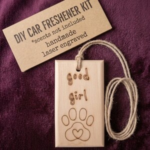 May include: A DIY car freshener kit with a wooden tag that reads "good girl" and features a paw print with a heart. The kit includes a tag, twine, and a card that says "DIY CAR FRESHENER KIT".