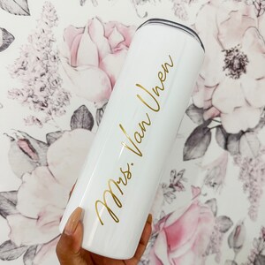 May include: White stainless steel tumbler with a gold inscription that reads "Mrs. Van Uhren".