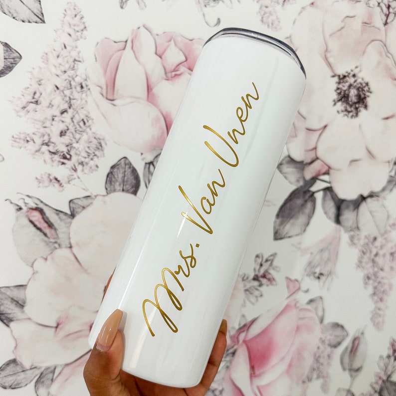 May include: White stainless steel tumbler with a gold inscription that reads "Mrs. Van Uhren".