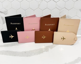 Op de afbeelding: Set van zes paspoorthouders in zwart, roze, bruin en beige met het woord "PASSPORT" in reliëf in gouden letters. Elke paspoorthouder heeft een gouden vliegtuigicoon.