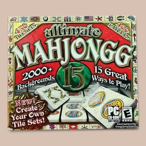 May include: The Ultimate Mahjongg 15 PC CD-ROM software box features a red background with gold lettering. It highlights 450 tile sets, 400 layouts, and 2000+ backgrounds. The cover displays white mahjong tiles with symbols and an ESRB Everyone rating.