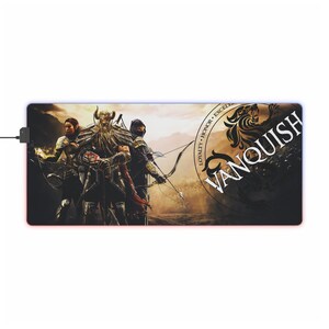 Puede incluir: Un tapete de ratón para juegos negro y dorado con una ilustración de fantasía de tres guerreros. El tapete de ratón tiene un borde azul y rojo brillante y el texto "VANQUISH" en un círculo con las palabras "LOYALTY, HONOR, EXCELLENCE" alrededor.