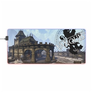 May include: A blue and red gaming mouse mat featuring a medieval castle scene and a circular logo that says "Vanquish" with the text "Our blood runs blue, loyalty holds for excellence, born in the ash, dragonclaw clan, and mist."